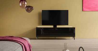 Sortbrun og lyst træ TV-møbel med fladskærm, i et beige rum med parketgulv, rosa væg og glaspendellamper