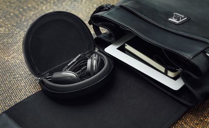 Otevřená hi-fi sluchátka Bowers & Wilkins P3 S2 černá, pohled shora, položená na černé kožené brašně, sluchátka složená