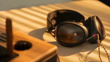 Cuffie in legno con cuscinetti in pelle, posate su un tavolo in legno chiaro, viste di tre quarti di fronte