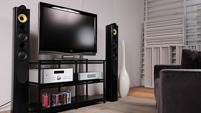 Rotel RB-1562 sort effektforstærker, set forfra, med tv, højttalere, tv-møbel og hylde