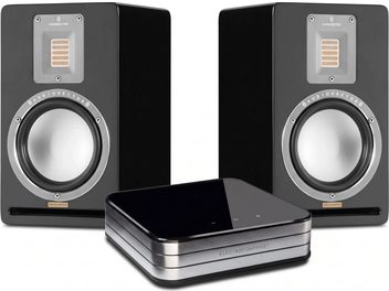 Två svarta Audiovector Special Edition-högtalare med silverfärgade högtalarelement, med en Electrocompaniet-apparat i förgrunden