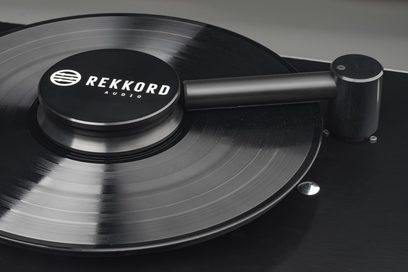 Vinylová deska Rekkord Audio RCM, detailní pohled shora, raménko a kruhový kovový otočný talíř s kartáčovaným povrchem