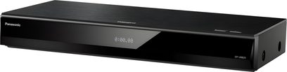 Leitor Blu-ray 4K Panasonic DP-UB820EFK preto em metal escovado, painel frontal em plástico preto brilhante com logotipo Panasonic à esquerda, visor digital central, dois botões no canto superior direito e lateral direita perfurada, vista em perspectiva frontal direita