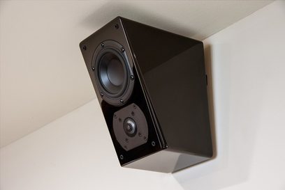 Reproduktor SVS Prime Elevation v černém lesklém provedení, pohled zepředu v perspektivě, viditelný tweeter a woofer, černá lichoběžníková skříň