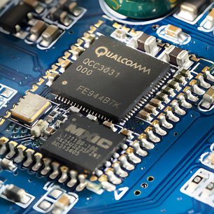 Blå printplade med elektroniske komponenter og Qualcomm QCC3031-chip i midten