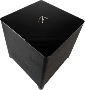 Cassa subwoofer Dynamo Foundation 12, vista angolata leggermente dall'alto, superficie superiore nera lucida con logo centrale, lati testurizzati scuri, angoli arrotondati, piedini discreti.
