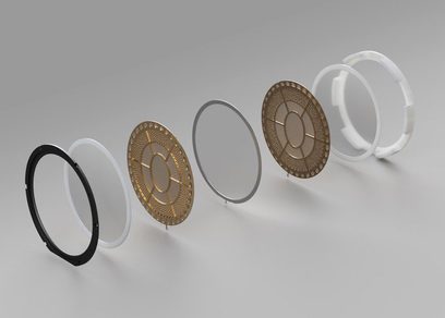 Fem gylne, gjennombrutte metallringer i ulike diametre, fra minste til største, plassert på rekke i profil mot en ensfarget grå bakgrunn