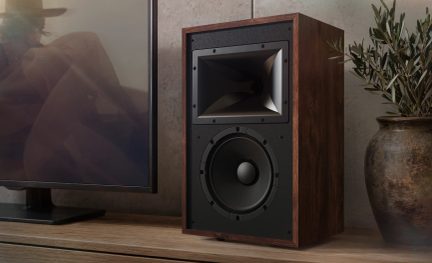 Diffusore hi-fi da scaffale nero con finitura in legno scuro, con tromba per gli alti e grande altoparlante frontale accanto a un televisore