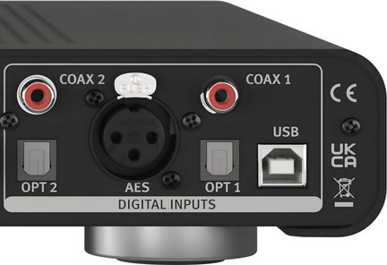 Vue arrière d'un panneau noir avec connecteurs marqués COAX 1, COAX 2, OPT 1, OPT 2, AES, USB et inscriptions UKCA, CE