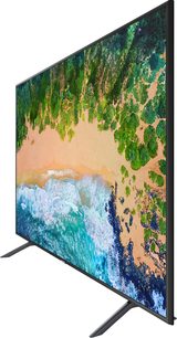Samsung UE49NU7105 fladskærms-TV, der viser et levende billede af et landskab med skov, strand og hav i klare farver