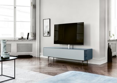 Lav grå og blå TV-møbel Spectral Scala SC1654 med skuffe og dør, på parketgulv i et moderne og lyst interiør