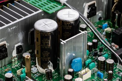 Grønne elektroniske kretser med svarte og sølvfargede elektrolyttkondensatorer på et trykt kretskort
