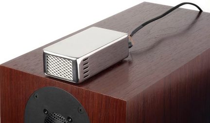 Super tweeter argentato con griglia frontale, appoggiato su un diffusore marrone e collegato tramite un cavo nero