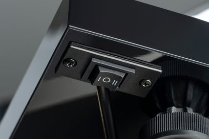 Hi-fi vinylspiller Triangle Lunar 3, nærbilde av en svart bryter med 2 synlige skruer på en glatt overflate