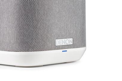 Witte slimme luidspreker Denon Home 150, lichtgrijze stoffen grille, close-up van de voet met blauw LED-lampje