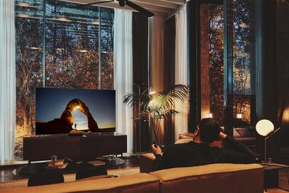 Samsung 65QN700B 2022 fladskærms-TV, der viser et naturligt landskab i en moderne stue med glasvægge og stueplanter