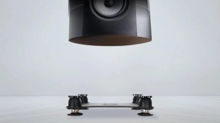 Supporto antivibrazioni nero per diffusore a quattro piedini, sotto un diffusore nero sospeso su sfondo grigio chiaro