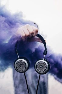 Offener Grado SR325x Kopfhörer, in einer Hand gehalten vor bewölktem Himmel, Frontalansicht in Großaufnahme