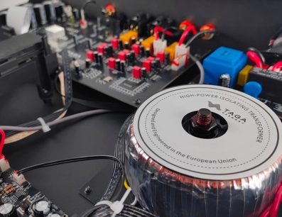 Lettore CD hi-fi Taga Harmony TCD-70T argento, vista interna, trasformatore isolante cilindrico, circuiti stampati neri, componenti rossi, gialli, blu, cavi neri e bianchi fissati con fascette, connettori visibili