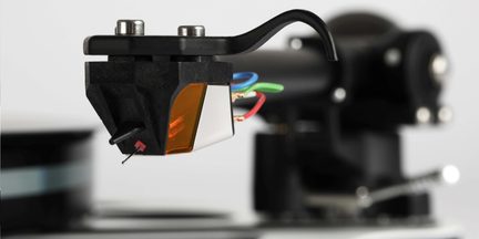 Sort pladespiller-pickup med diamant og farvede kabler, close-up af tonearmen