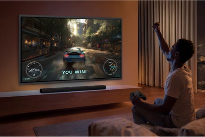 Samsung TV TQ677S99H 2026 stor vægmonteret skærm med racerspil vist i en moderne stue