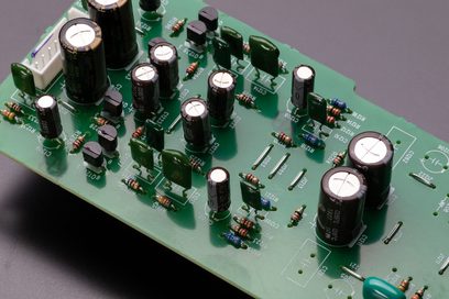 Zelený tištěný spoj s několika černými elektrolytickými kondenzátory a hnědými rezistory, detailní pohled shora