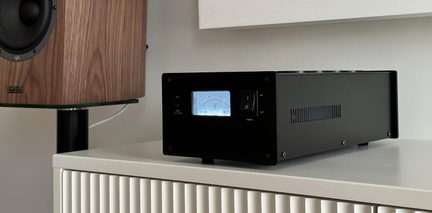 Scatola nera in metallo, vista a tre quarti, voltmetro retroilluminato, interruttore I/O, feritoie di aerazione laterali