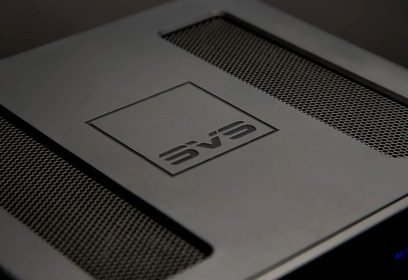Bezdrátový vysílač SVS Prime SoundBase v černé barvě, detailní pohled shora se zaměřením na reliéfní kovové logo