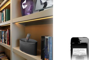 Bowers & Wilkins Z2 sort dockingstation i sort på hylde med bøger, fjernbetjening og smartphone, der viser stemmebeskeder