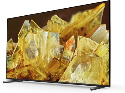 Sony XR85X90L fladskærms-tv set fra trekvart vinkel med gule krystaller, sort ramme, metalstativ