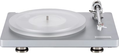 ClearAudio Compass hi-fi platenspeler, frontaal en licht van bovenaf gezien, rechthoekig chassis van matgrijs aluminium op ronde metalen pootjes, ronde draaitafel van transparant acryl en zilverkleurige toonarm