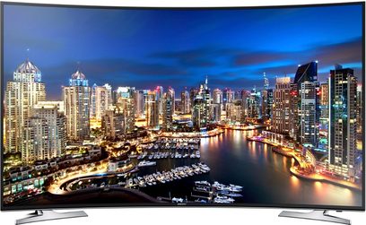 Samsung UE65HU7100 buet TV, der viser et natligt vue af oplyste skyskrabere og både i en marina