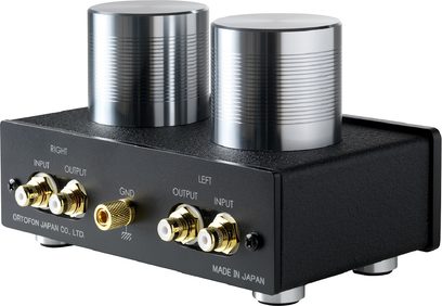Center til pladespiller Ortofon ST-80 SE, set fra trekvart vinkel, 2 sølvfarvede metalcylindre, 4 forgyldte RCA-stik, 1 forgyldt GND-stik, sort kabinet, inskription "MADE IN JAPAN"
