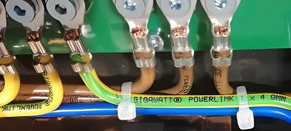 GigaWatt PF-1 EVO 4-fach-Steckdosenleiste mit grünen und gelben Netzkabeln, Nahaufnahme von vorne auf grünem Hintergrund