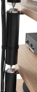 Dodatečná police pro hi-fi nábytek Norstone Design Copenhagen 2 černá / dub, detailní pohled na černý válcový sloup s kovovými hroty, světlý dřevěný panel, potažené kabely upevněné popruhem, viditelné audio konektory na přilehlém zařízení