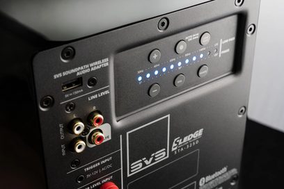 SVS SB-1000 PRO subwoofer med högblankt vitt pianolackerat hölje, bakre panel med anslutningar och ljudkontroller, blå lysdioder tända