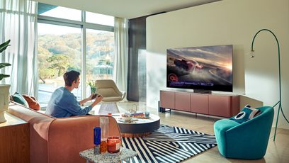 Moderne stue med brun læderlænestol, turkis lænestol, sort-hvidt zebramønstret tæppe og et stort fladskærms-tv, der viser en racerbil