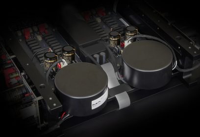 Indvendigt vue af en Matrix Audio MP‑1 forforstærker, to sorte toroidale transformatorer under metalkappe, sorte cylindriske "Mundorf" kondensatorer, sorte aluminiumkøleprofiler og flade kabelbånd, set i trekvart fugleperspektiv