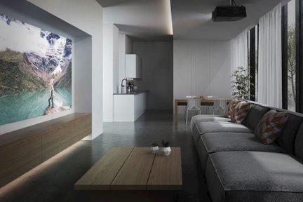 Moderne stue, gråt betongulv, stort gråt stofsofa, træbord, vægmonteret skærm, projektor i loftet