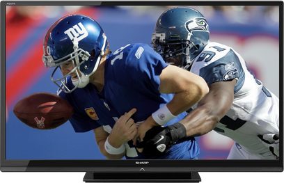 Sharp LC-60LE635E-fladskærm viser to amerikanske fodboldspillere, hvor den ene fra New York Giants tackler den anden fra Seattle Seahawks