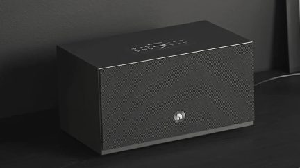 Coluna sem fios Audio Pro preta, frente com grelha perfurada e comandos na parte superior, vista a três quartos