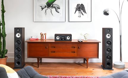 Impianto hi-fi Triangle con due diffusori da pavimento neri e canale centrale su mobile TV in legno stile scandinavo