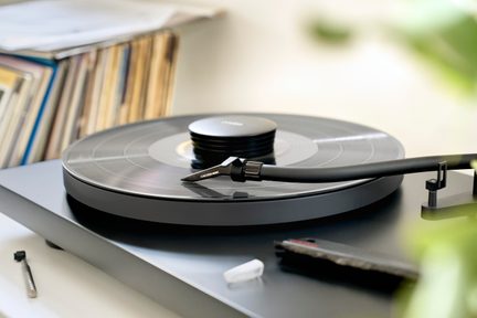 Černý vinylový přehrávač s přehrávanou deskou, viditelným ramenem a jehlou, detailní záběr