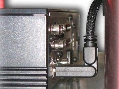 Metalmekanisme indeni et elektronisk apparat med tandhjul, fjedre og sort rektangulært stik