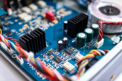 Blå printplade med elektroniske komponenter, sorte og grønne kondensatorer, flerfarvede snoede ledninger