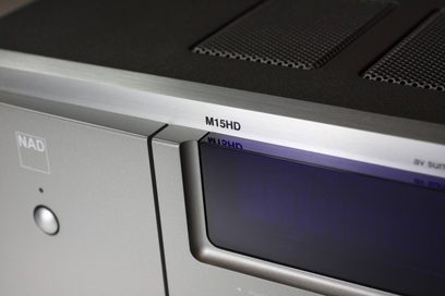 NAD M15HD hjemmebiografsforstærker, frontpanel i børstet aluminium med blå skærm og hvid "M15HD"-skrift