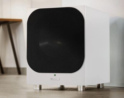 Hvid Canton-subwoofer med afrundet sort front på cylindriske metalfødder, set i trekvart profil