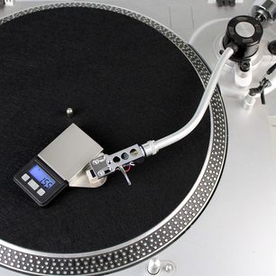 Sort pladespiller med sølvfarvet tonearm og kontravægt, Enova HIFI BPC 5 digital justeringsvægt i forgrunden