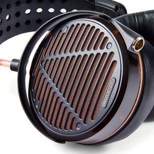 Audeze LCD-5s hi-fi austiņas tuvplānā ar atvērtu melnu ausi, vara režģi un perforētu galvas stīpu