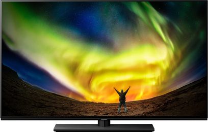 Panasonic TX-48LZ980E TV-skærm, der viser gul og grøn nordlys på en stjerneklar himmel, menneskelig silhuet i et ørkenlandskab
